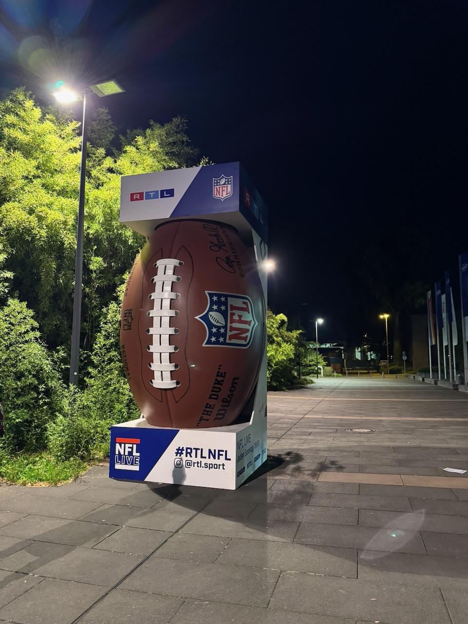 Große NFL-Football-Dekoration mit RTL-Logo vor dem Sendezentrum bei Nacht